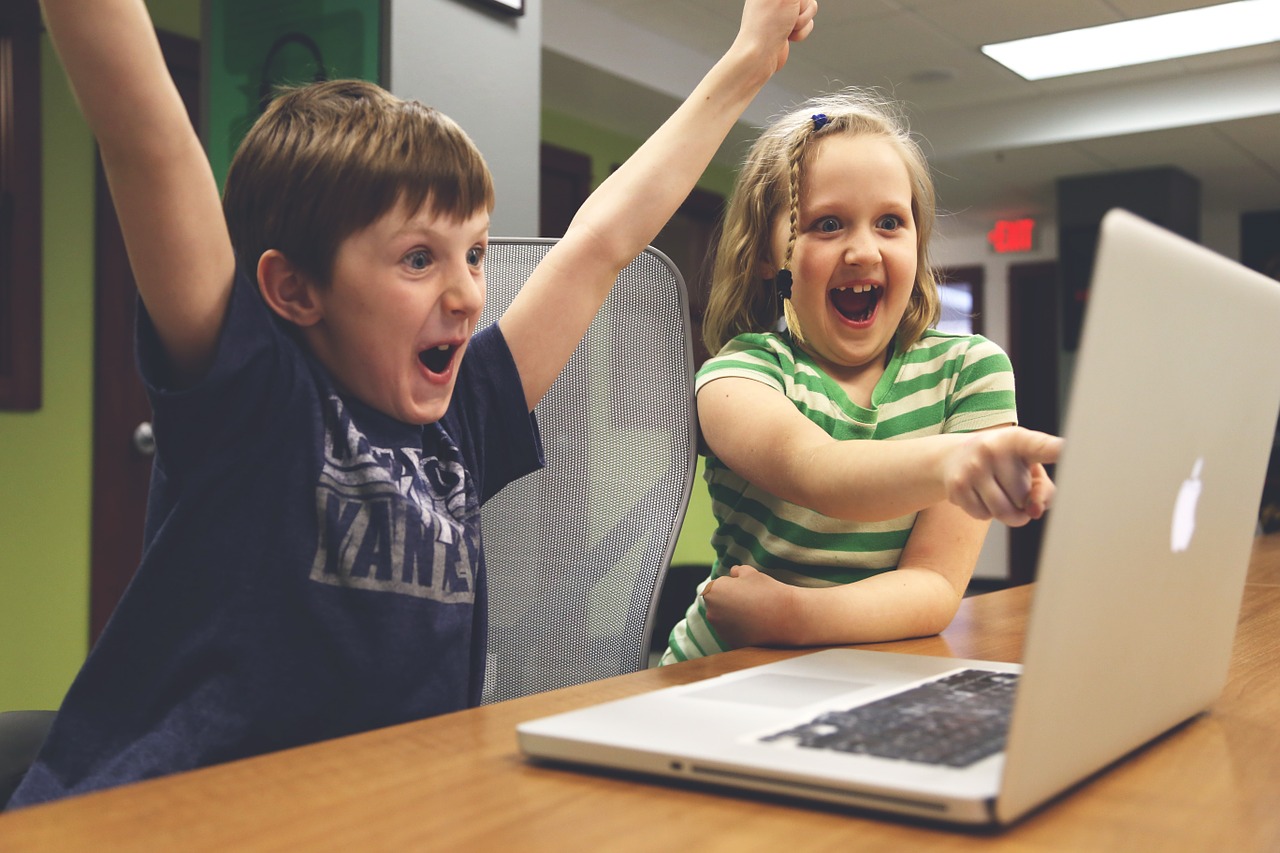 パソコンを見ながら喜ぶ子供たちの画像